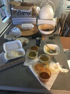 Photograph of my concrete table with curry containers strewn over it and partially eaten food.