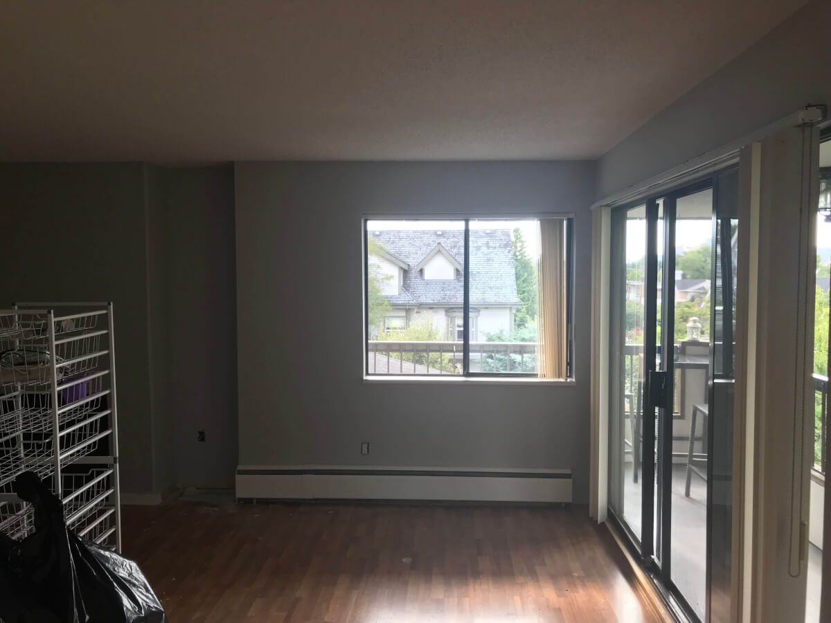 Photo during renovation from my dining area to my lounge with a double window in the background. The walls are now a light grey and the ceiling is very nearly white. The flooring is the same dark brown laminate.