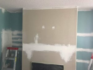 Photo of the area above the fireplace just after the first patching after removing the fireplace and knocking down the shelves. The ceiling has also had the first coat of off-white paint.